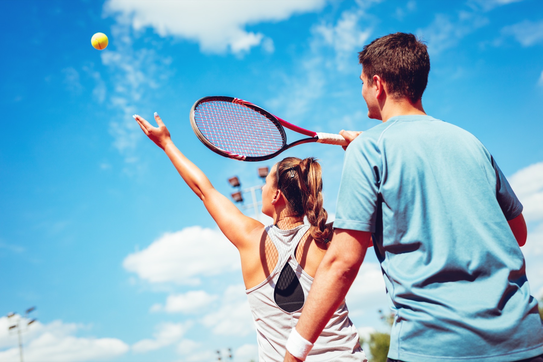 A coach guiding a player's serve.
