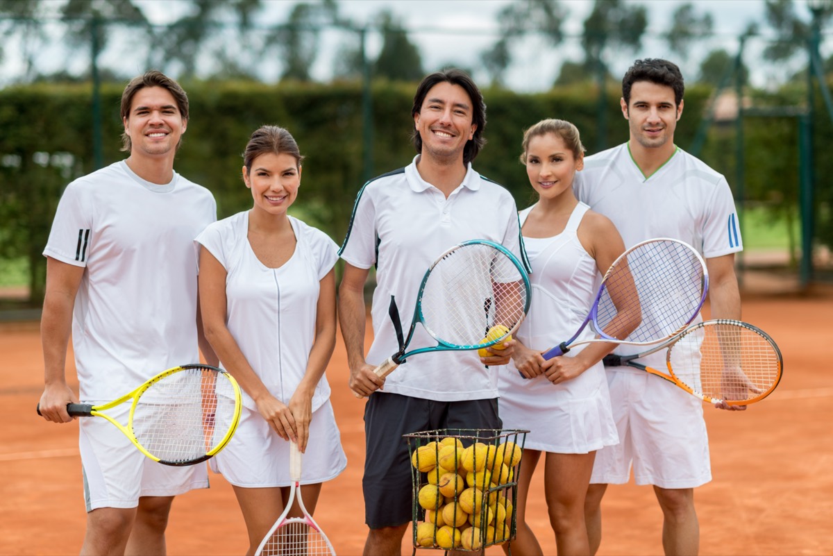 A group class warming up together on a tennis court.