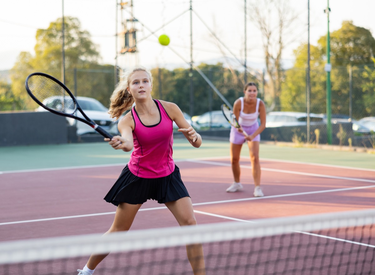 Two players in a doubles rally during a daytime match.